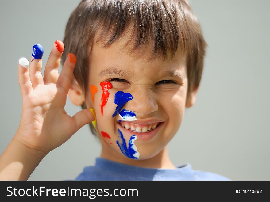 Kid with color on his fingers and face smiling