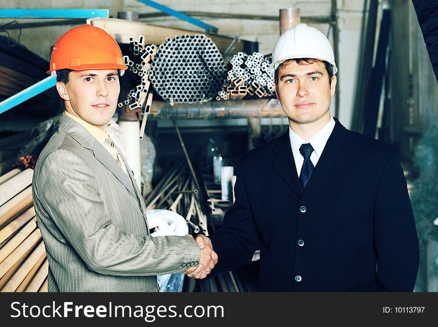 Industrial theme: two businessman shaking their hands at a manufacturing area. Industrial theme: two businessman shaking their hands at a manufacturing area.