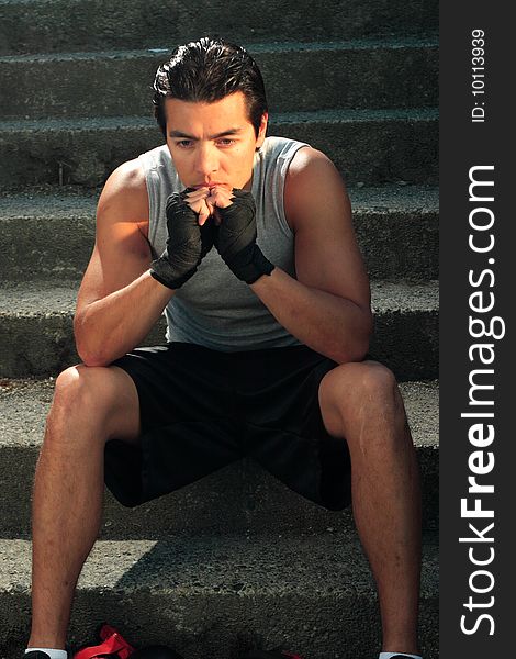 A boxer sitting on stairs with his head resting in hands. A boxer sitting on stairs with his head resting in hands