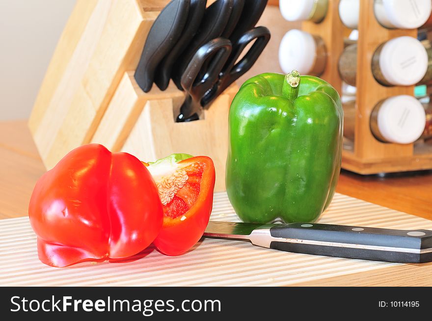 An image of red and green peppers to be cut on a chopping board. An image of red and green peppers to be cut on a chopping board.