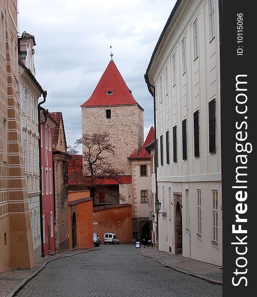 Streets of Prague. Czechia. Tower with a red, peaked roof on a background of the blue sky