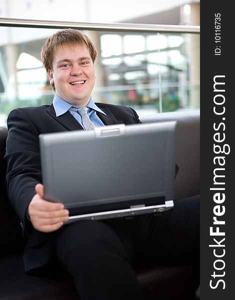 Happy young businessman with laptop in business building