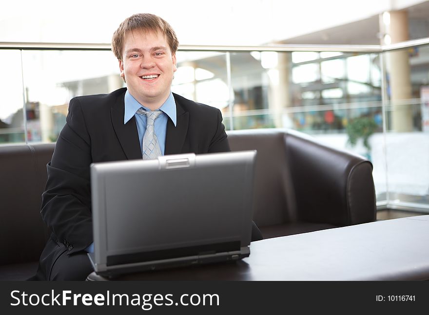 Happy young businessman with laptop in business building