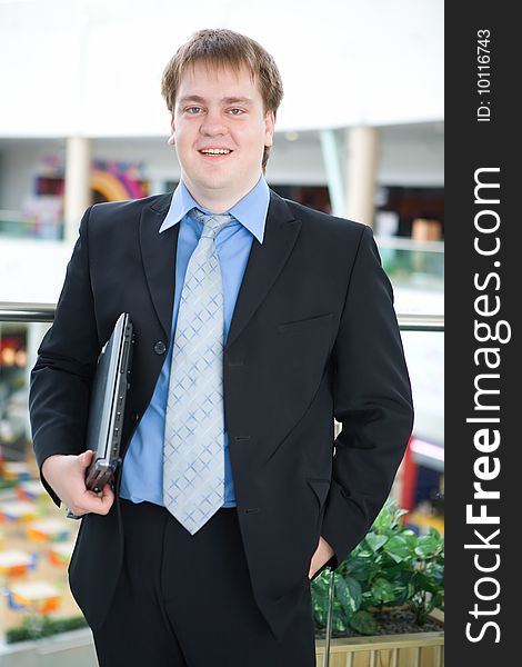 Happy young businessman with laptop in business building