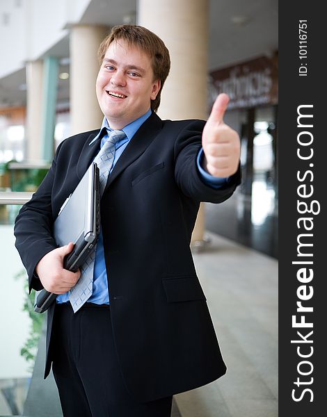 Happy young businessman with laptop in business building