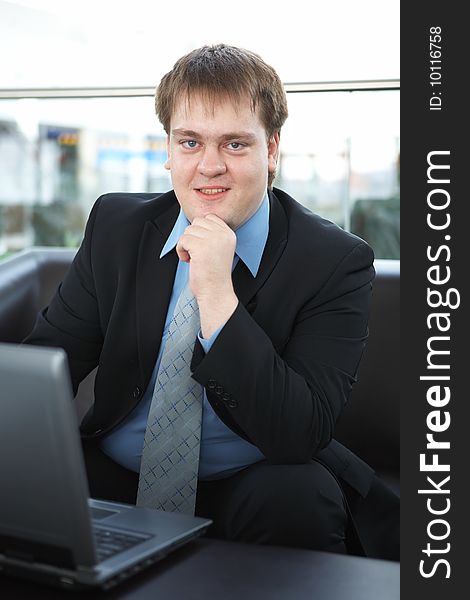 Happy young businessman with laptop in business building