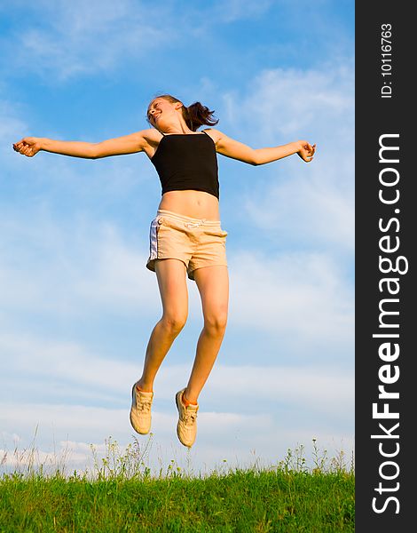 Happy young woman is jumping on green grass