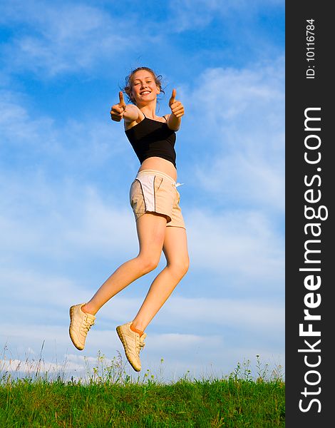 Happy young woman is jumping on green grass