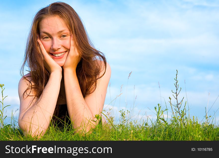 Young woman lying on the green grass under blue sky