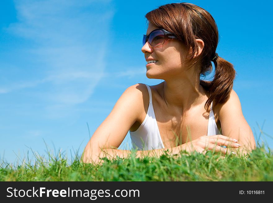 Young woman lying on the green grass under blue sky