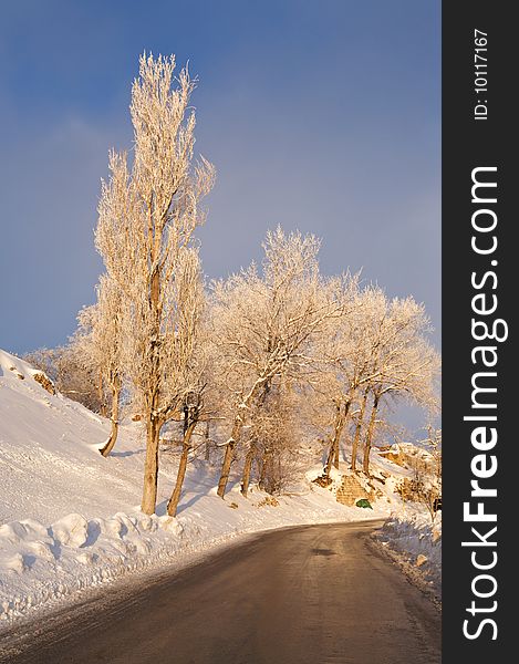 At the time of sunset. Mountain road in the winter. On the margins of snow-covered trees. At the time of sunset. Mountain road in the winter. On the margins of snow-covered trees.