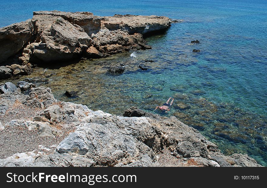 Rocks in shallow waters of Mediterranean Sea an a man diving. Rocks in shallow waters of Mediterranean Sea an a man diving