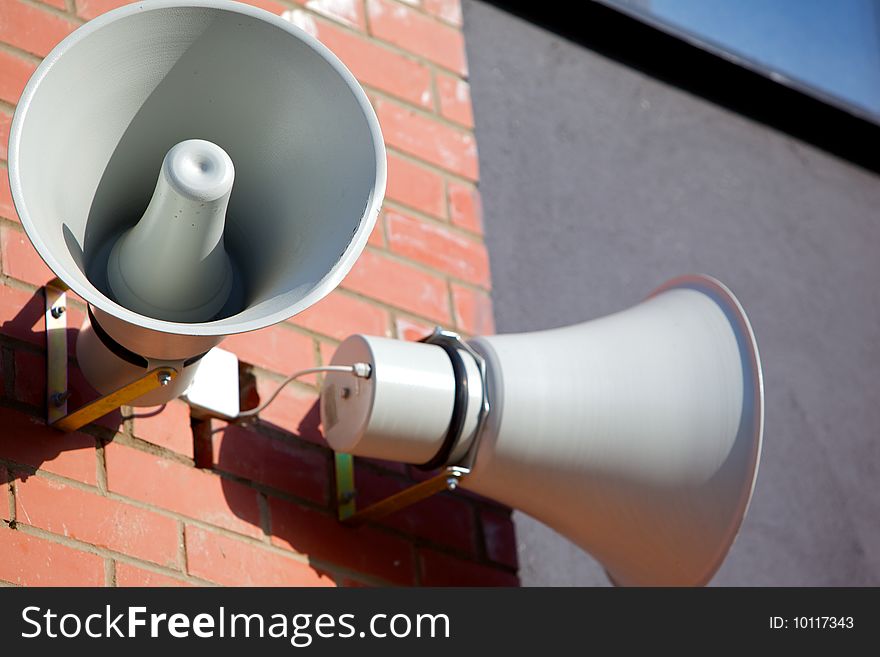 Two megaphone on the wall of a brick house on a background of blue sky. Two megaphone on the wall of a brick house on a background of blue sky