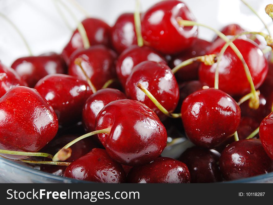 Cherry in the transparent plate against the white background. Cherry in the transparent plate against the white background