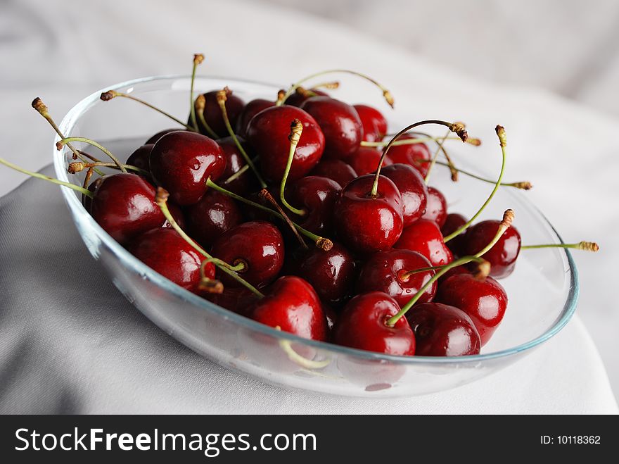 Cherry in the transparent plate against the white background. Cherry in the transparent plate against the white background