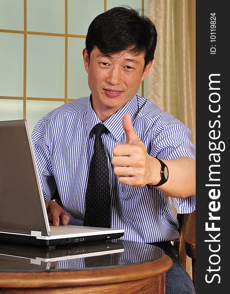 Businessman working with laptop and shows the OK sign - successful manager in the office with notebook