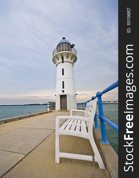 A scenic light house with a bench overlooking the vast ocean. A scenic light house with a bench overlooking the vast ocean.