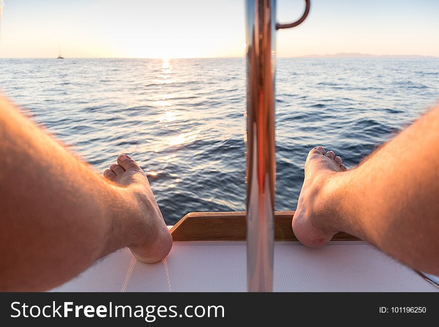 Feet of man with view of the sea and sunset.