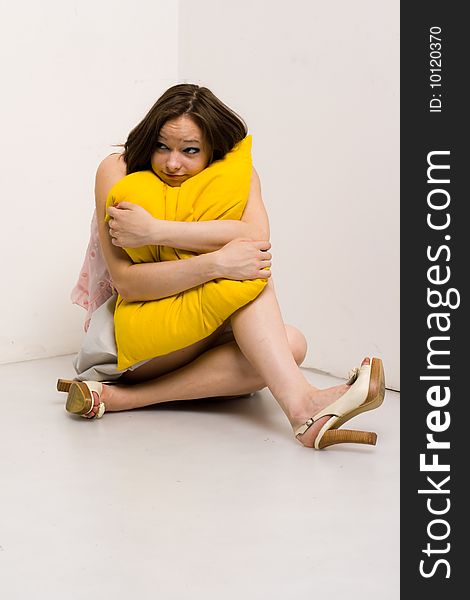 Pretty young girl with black hair isolated on white background, holding a yellow pillow. Pretty young girl with black hair isolated on white background, holding a yellow pillow