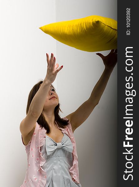 Pretty young girl with black hair isolated on white background, holding a yellow pillow. Pretty young girl with black hair isolated on white background, holding a yellow pillow