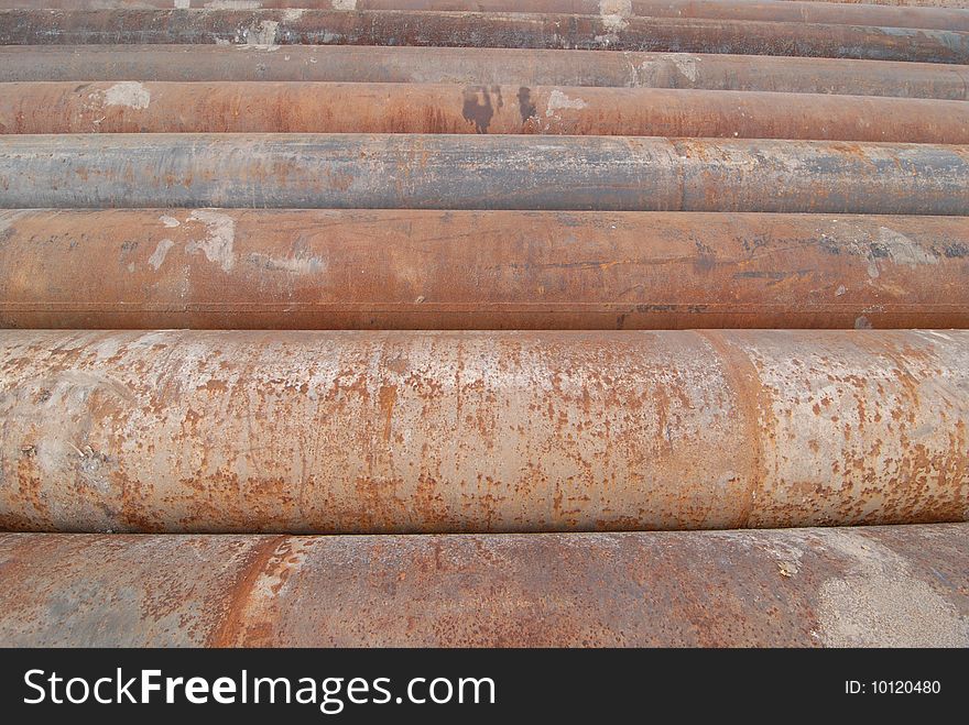 A group of large cast iron pipes lie in parallel after being used in a river dredging operation.