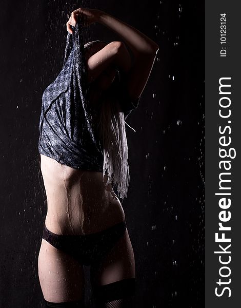 Girl undressing in the rain on black background. Girl undressing in the rain on black background