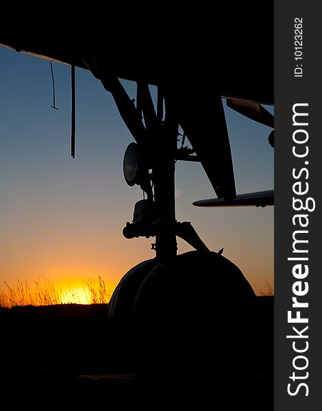 Aircraft nose wheel Silhouette against setting sun. Aircraft nose wheel Silhouette against setting sun