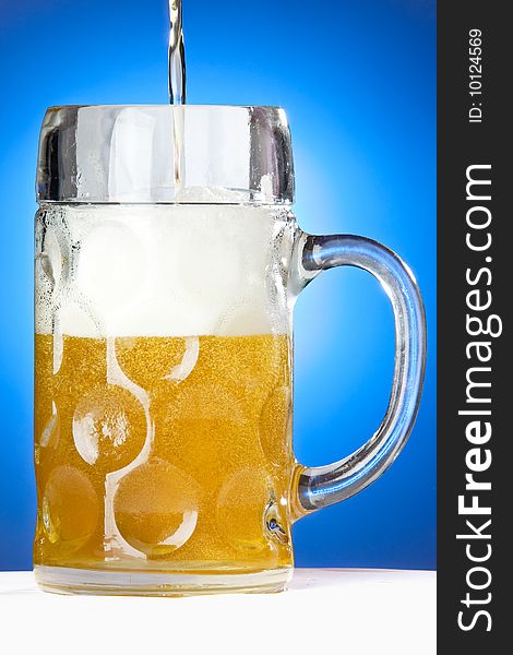 An Oktoberfest beer being poured on a blue background. An Oktoberfest beer being poured on a blue background.