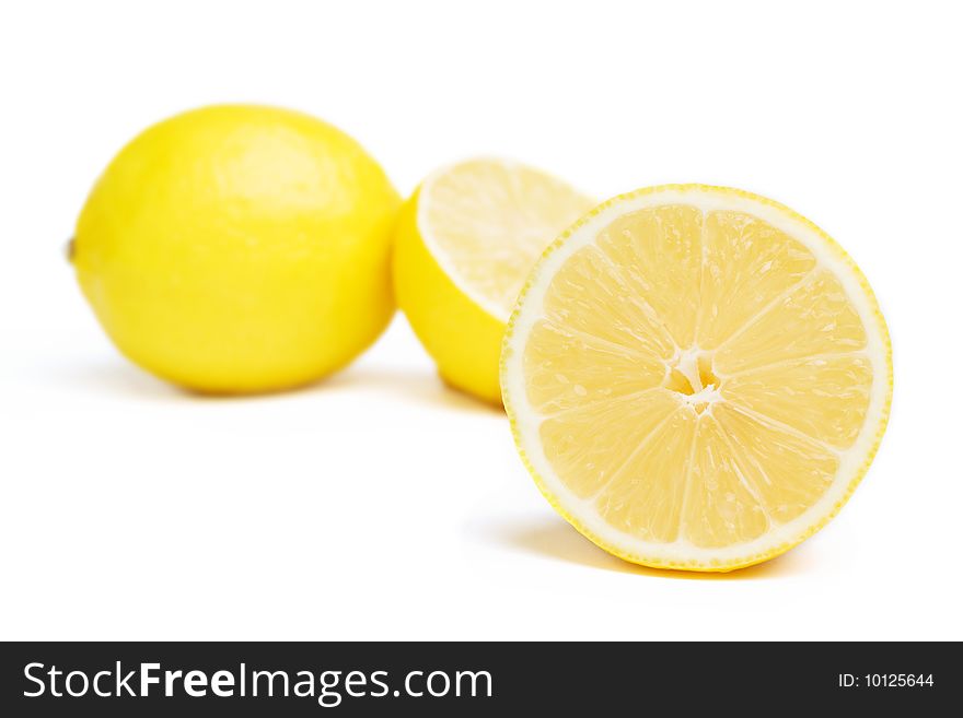 One lemon and two halfs isolated on white. Focus on front lemon. One lemon and two halfs isolated on white. Focus on front lemon.