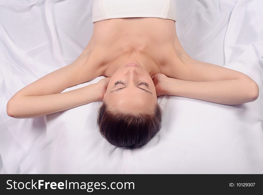 Portrait of the Fresh and Beautiful woman of the brunette laying on a white background