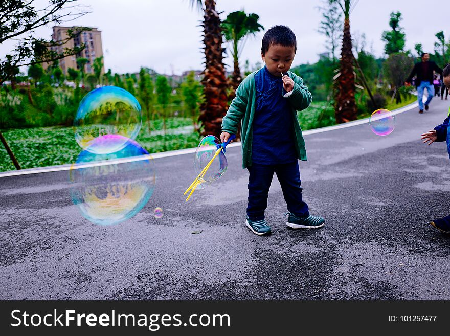 Little boy making soap bubbles on street