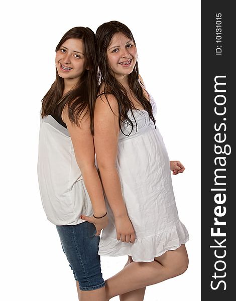 Two identical twin sisters with long brown hair smiling standing over white