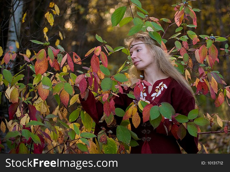 The blonde girle in medieval red dress in the autumn forest. The blonde girle in medieval red dress in the autumn forest
