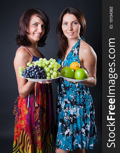 Two beautiful girls hold plates with fruits