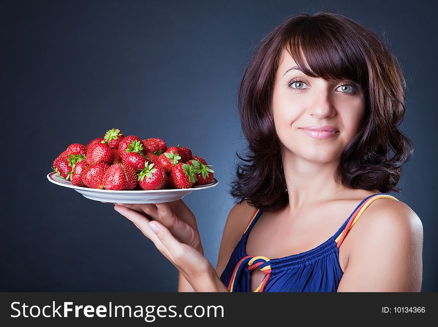 Beautiful girl holds a plate with a strawberry