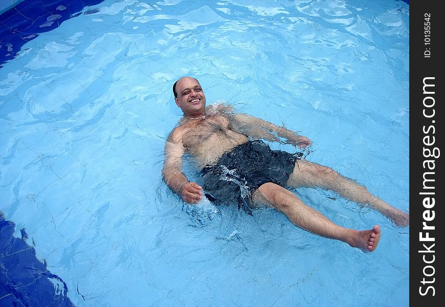 An aged person happily lying in the swimming pool. An aged person happily lying in the swimming pool.