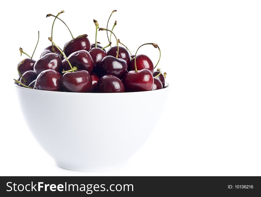 A white bowl full of dark cherries isolated on white. A white bowl full of dark cherries isolated on white.