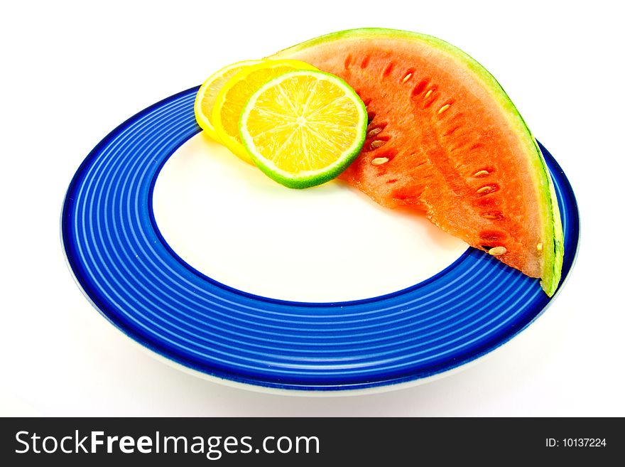 Slice of red juicy watermelon with lemon, lime and orange slices on a blue plate with a white background. Slice of red juicy watermelon with lemon, lime and orange slices on a blue plate with a white background