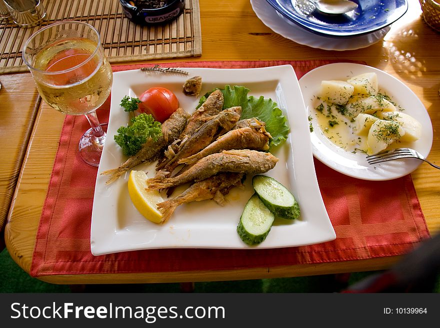 Fried fish and white wine on the table