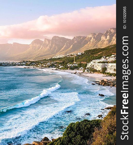 Waves crashing on the shores of a beautiful beach surrounded by mountains.