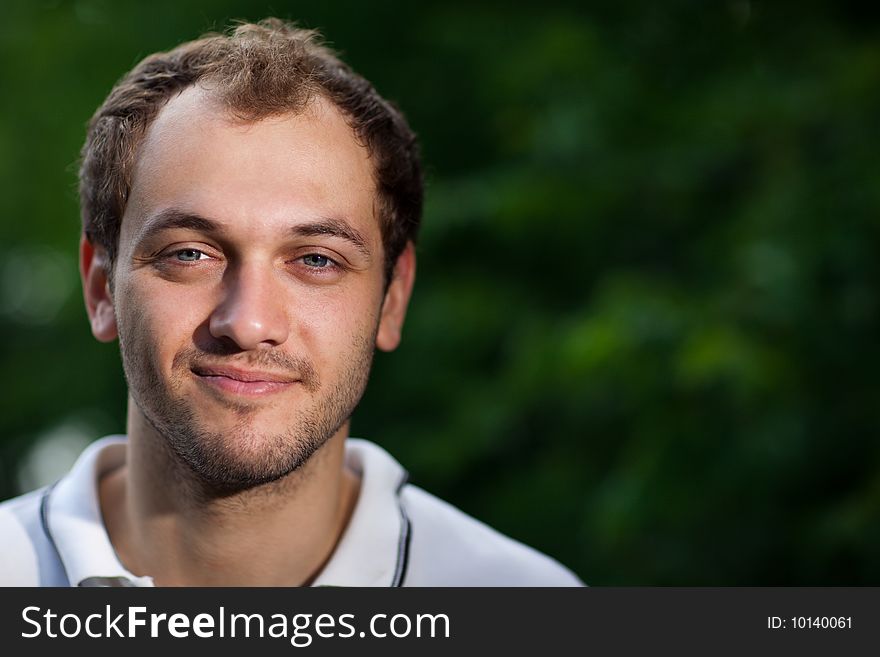 Portrait of a young man on green blurry background - shallow DOF, focus on eyes