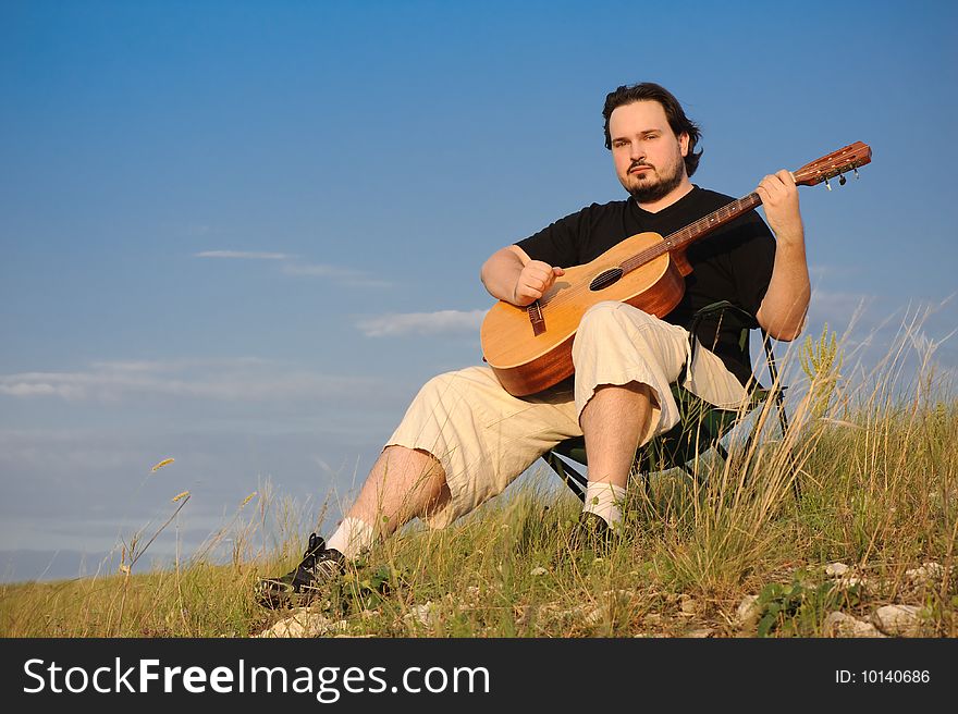 Man outdoors playing acoustic guitar, in rays of sunset. Man outdoors playing acoustic guitar, in rays of sunset