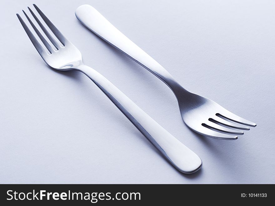 Elegant steel forks on white paper background. Elegant steel forks on white paper background