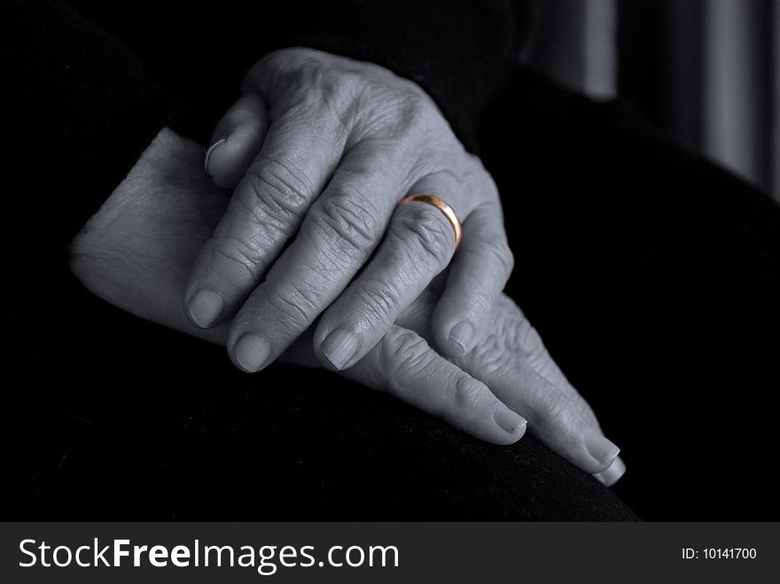 An old lady's hands on her lap in a pensive pose. Idea behind the image is the theme of contemplating time, the passing of many years of marriage accentuated by the gold ring. An old lady's hands on her lap in a pensive pose. Idea behind the image is the theme of contemplating time, the passing of many years of marriage accentuated by the gold ring.