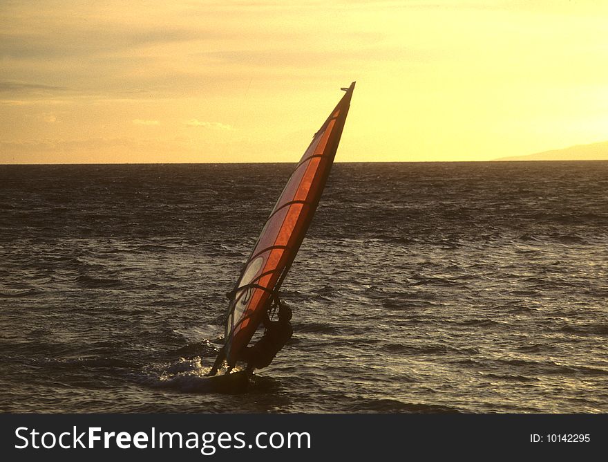 A lone windsurfer at sunset on the Pacific off the coast of Maui. A lone windsurfer at sunset on the Pacific off the coast of Maui.