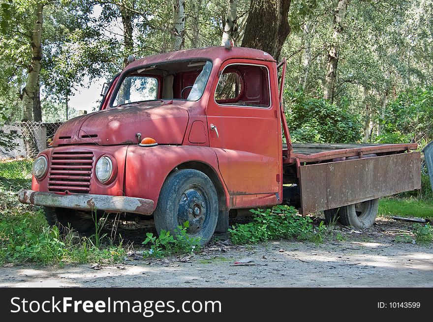 Grungy red old timer truck in the forest