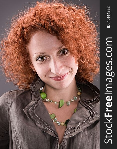Beautiful model with curly red hair on gray background.