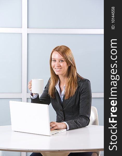 Business woman in modern office with laptop and coffee