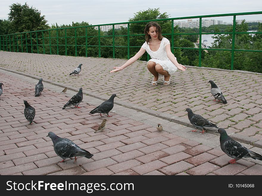 The nice girl feeds wild pigeons from a hand