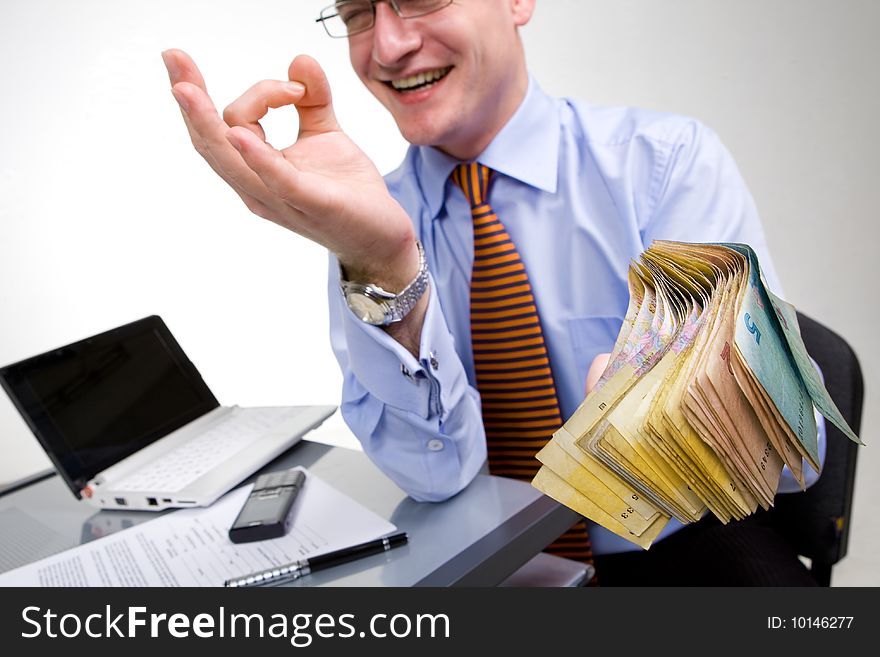 Businessman at work place holding bunch of money. Businessman at work place holding bunch of money
